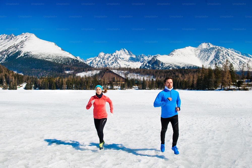 Young couple jogging outside in sunny winter mountains