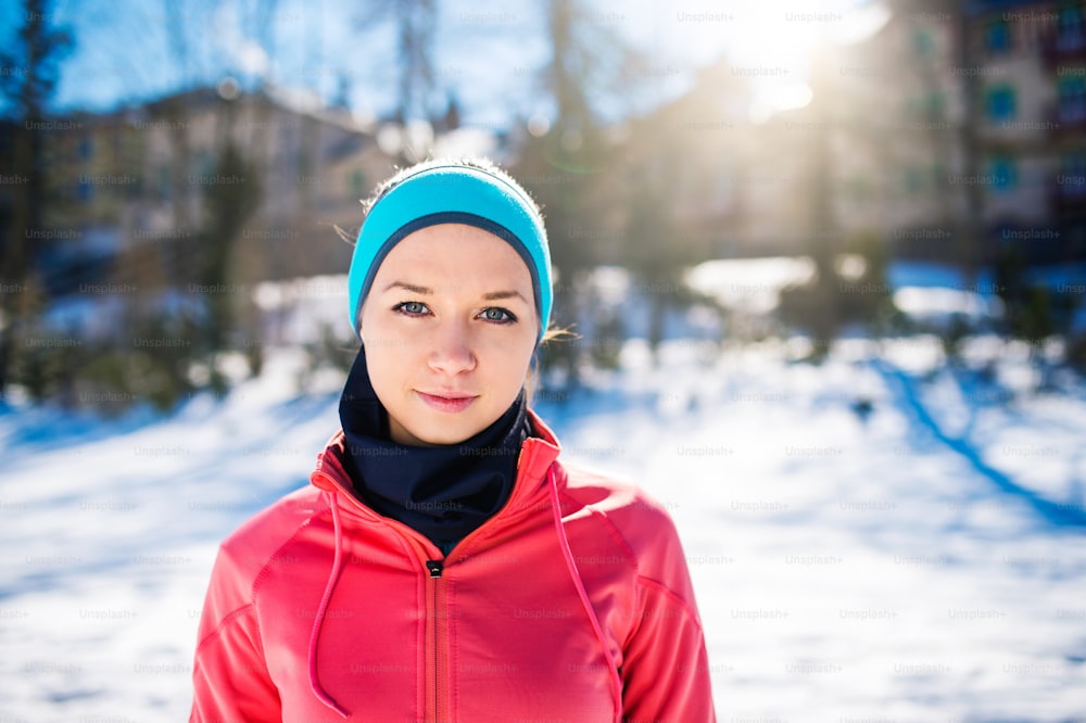 Young woman jogging outside in sunny winter mountains