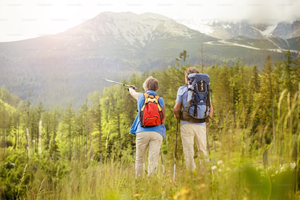 Pareja de turistas de la tercera edad haciendo senderismo en las hermosas montañas