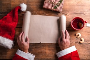 Père Noël tenant une liste de souhaits vide dans ses mains