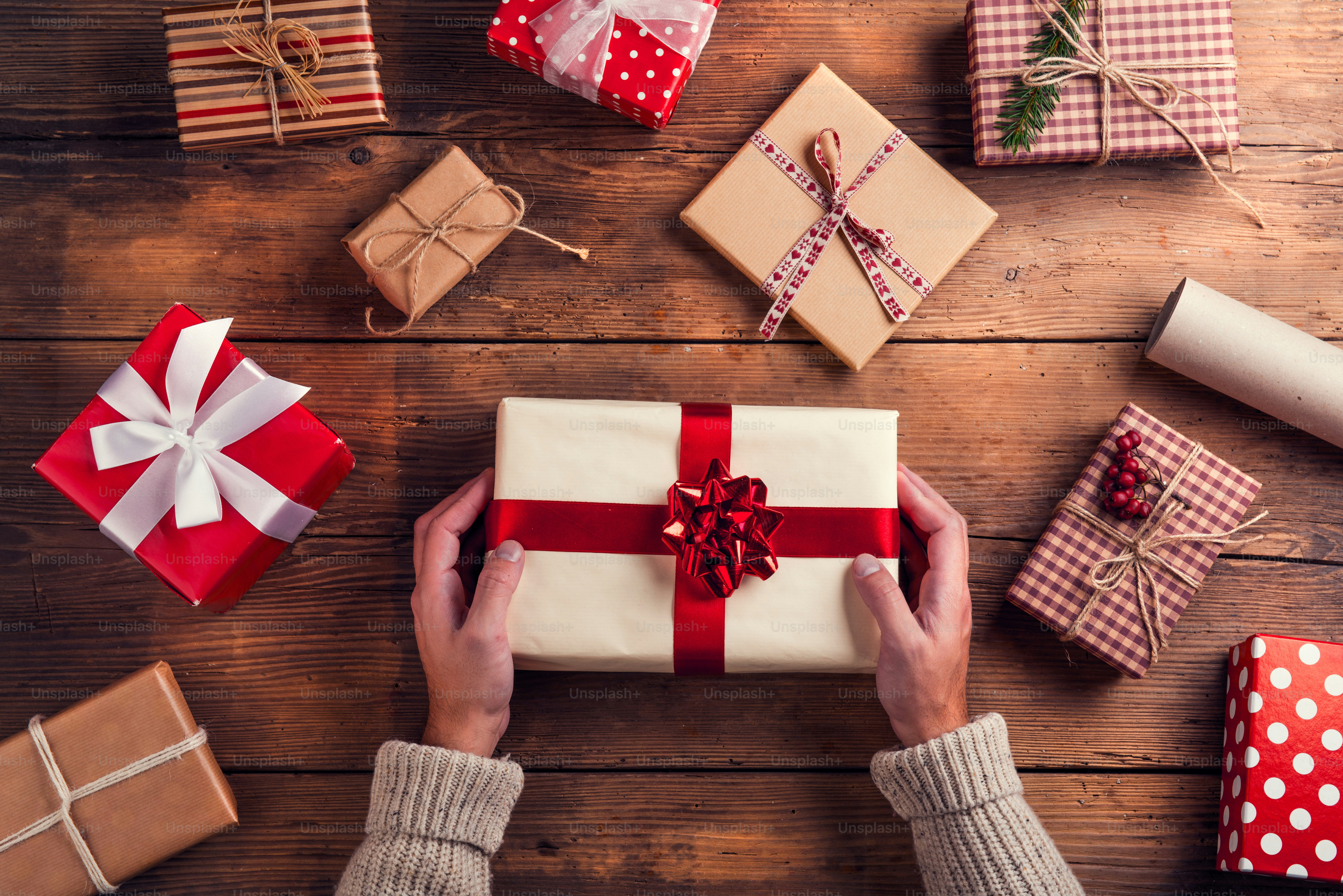 Man holding Christmas presents laid on a wooden table background