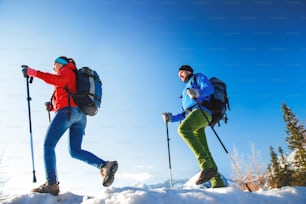 太陽の光が降り注ぐ冬の山々で外をハイキングする若いカップル