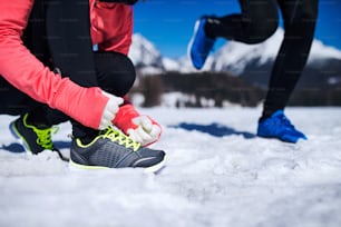 Giovane coppia che fa jogging fuori nelle montagne soleggiate di inverno