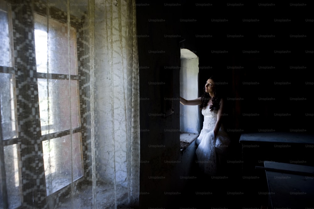 Lovely and happy brunette bride posing in old house