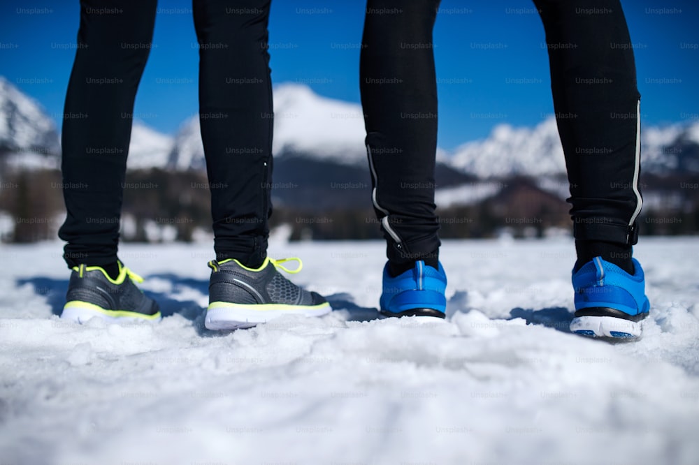 Giovane coppia che fa jogging fuori nelle montagne soleggiate di inverno