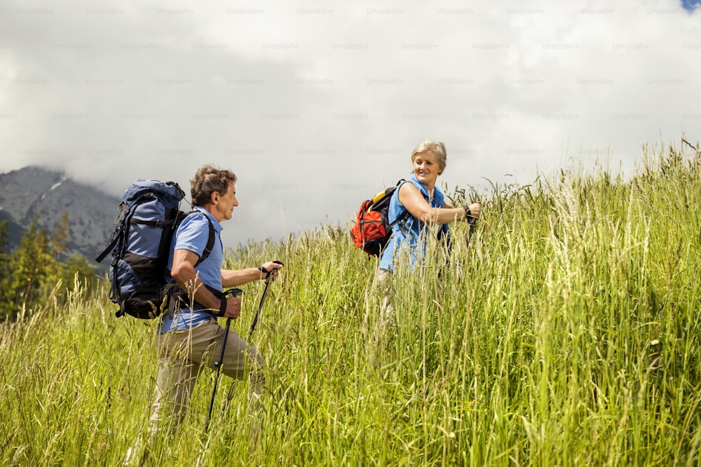 Senior tourist couple hiking at the beautiful mountains