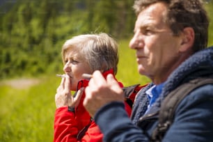 Senior hikers couple smoking during the walk in the mountains