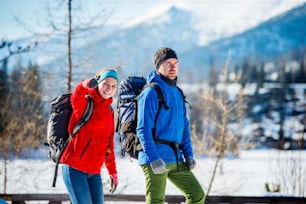 Casal jovem caminhando ao ar livre em montanhas ensolaradas de inverno