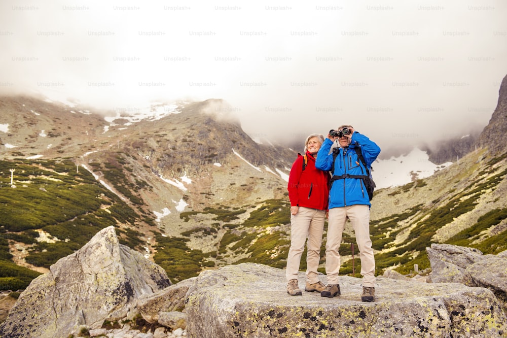 Senior hikers couple enjoying the landscape view with binoculars