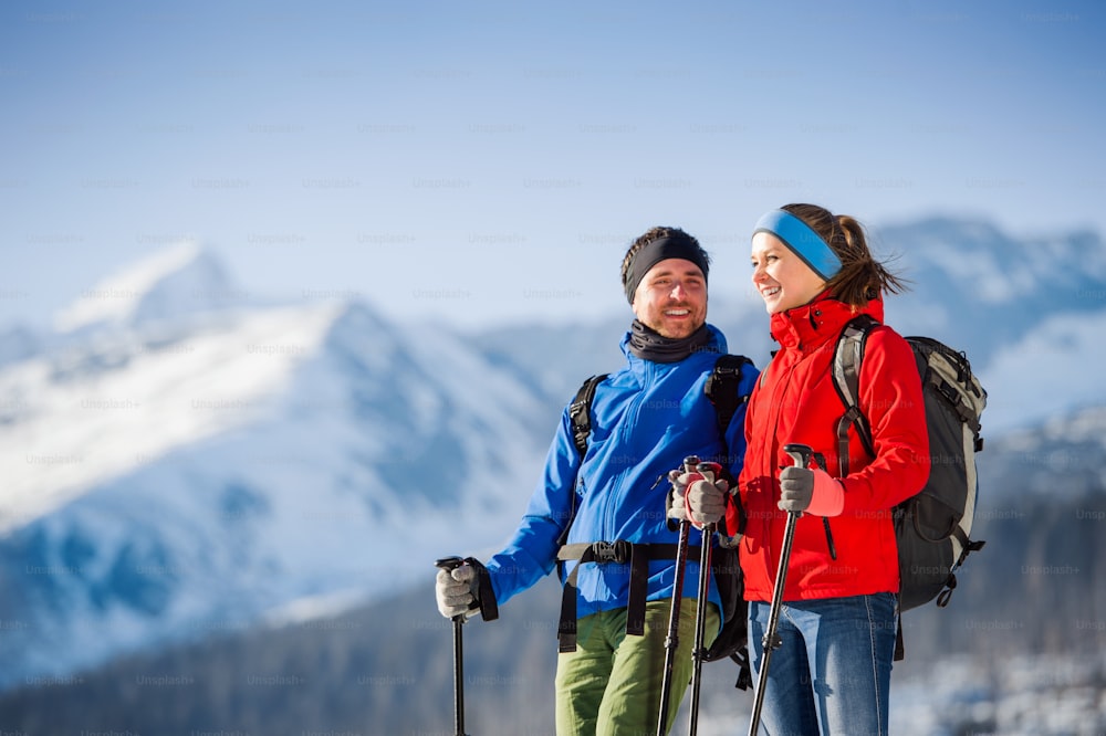 Young couple hiking outside in sunny winter mountains