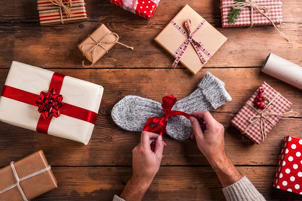 Man unwrapping Christmas present laid on a wooden table background