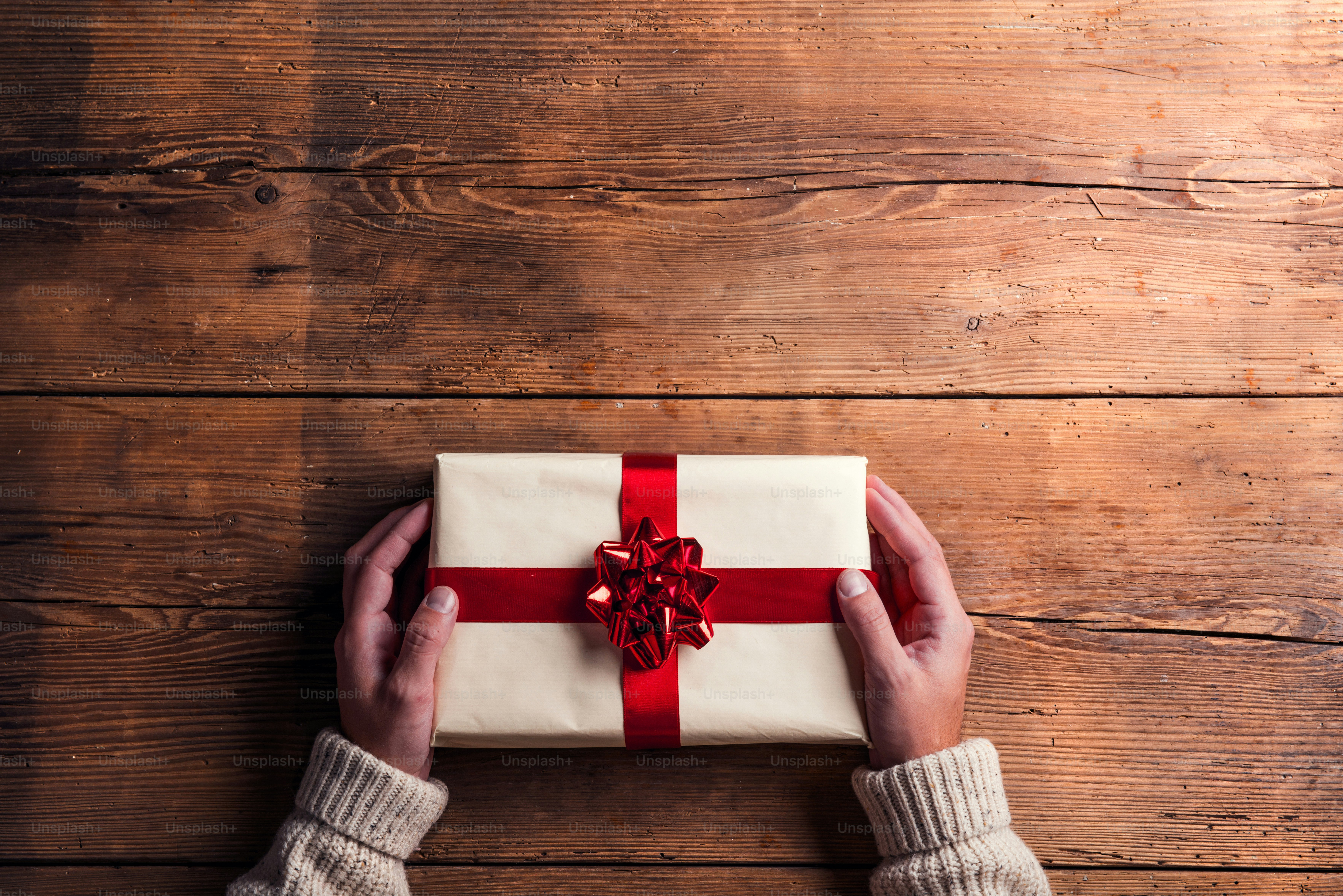 Man holding Christmas present laid on a wooden table background