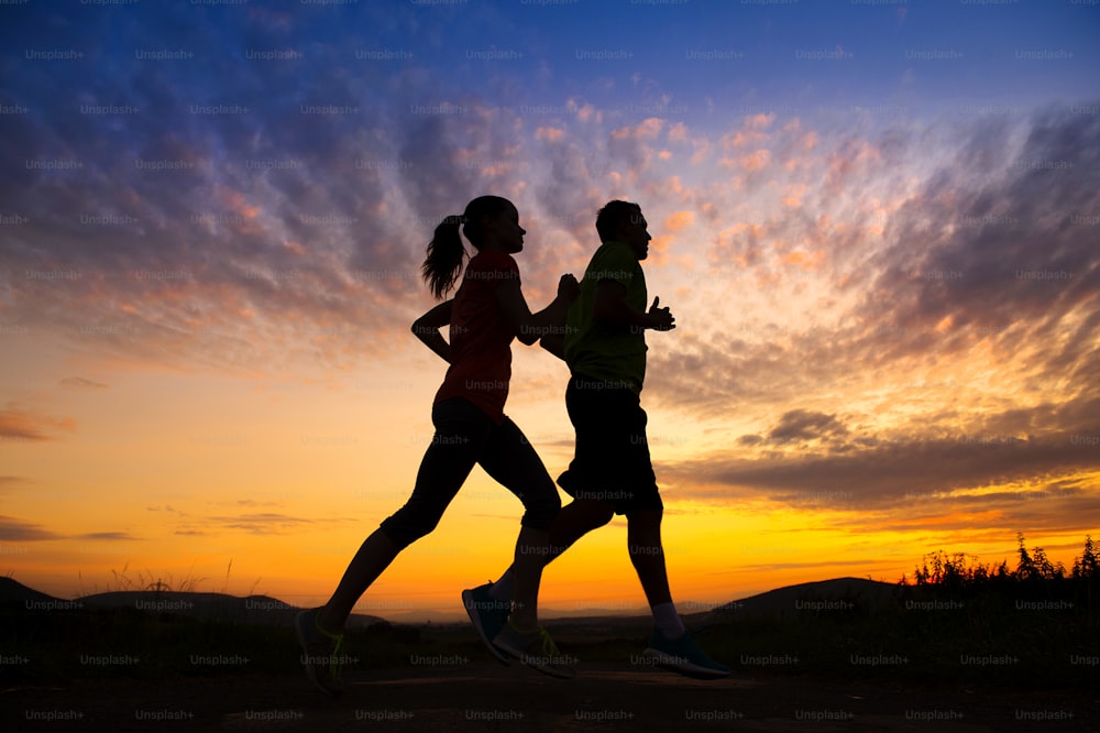 Silhouette of young couple running in sunset