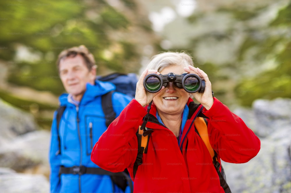 Coppia di escursionisti anziani che si godono la vista del paesaggio con il binocolo
