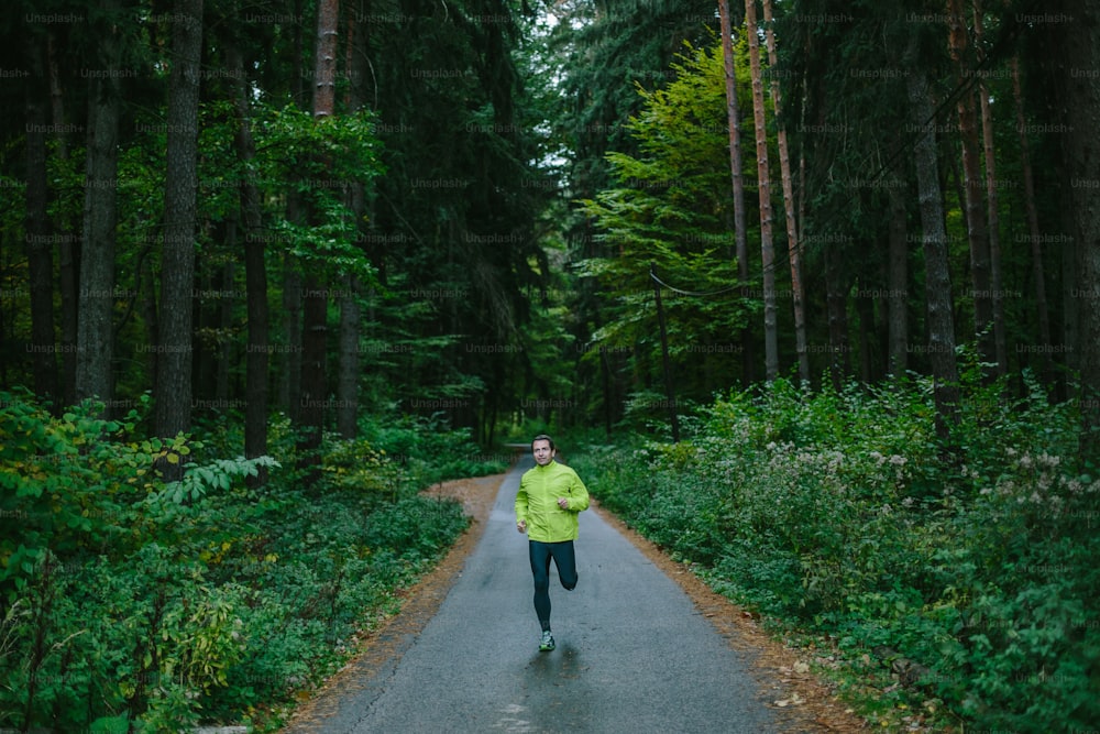 Man running and exercising for trail run on a path in an old green forest.