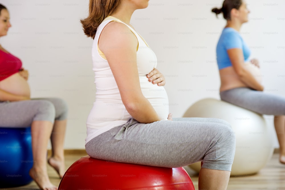 Young pregnant women doing exercise using a fitness ball