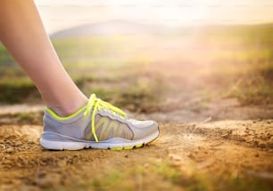 Runner woman feet running on countryside road, closeup on shoe