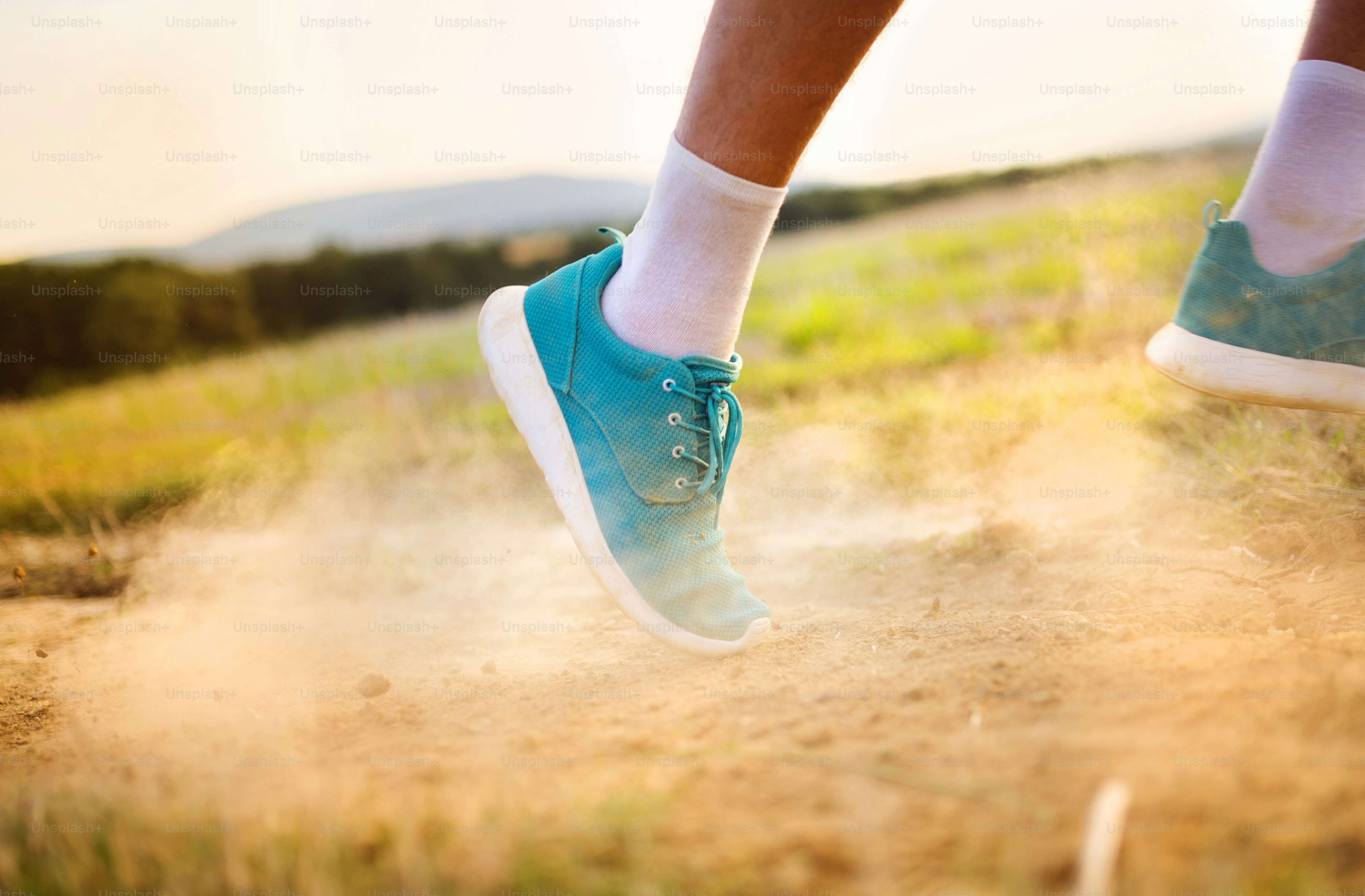 Runner man feet running on countryside road, closeup on shoe