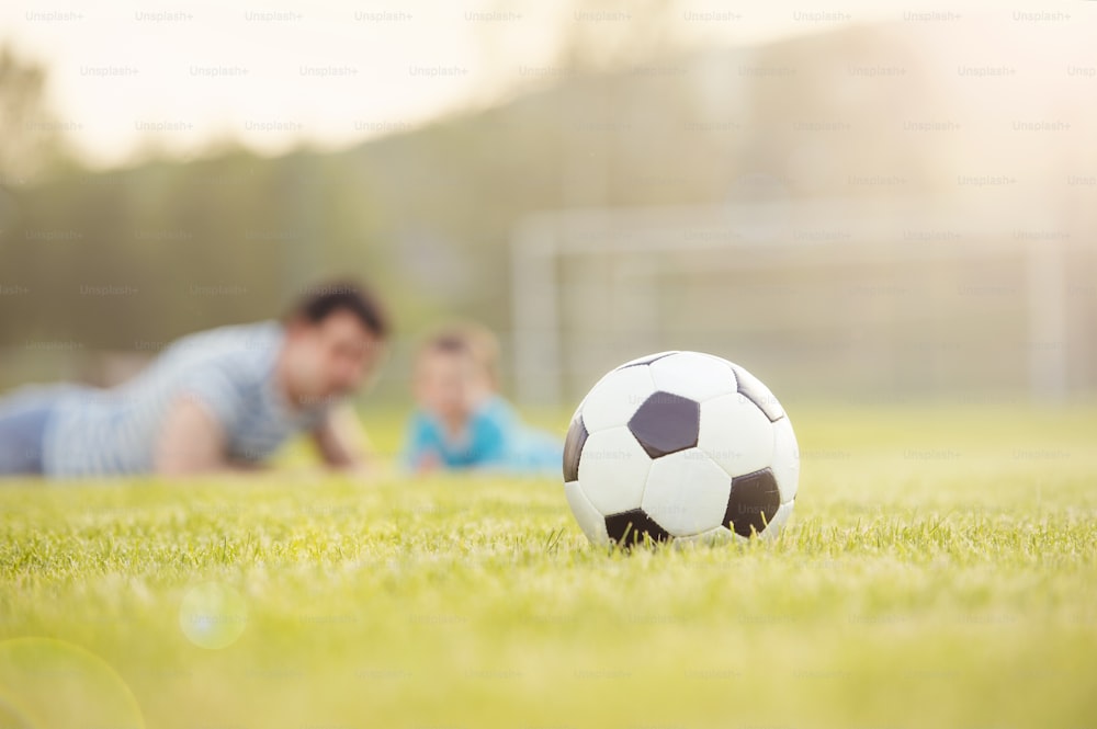 Giovane padre con il suo figlioletto che si diverte sul campo da calcio