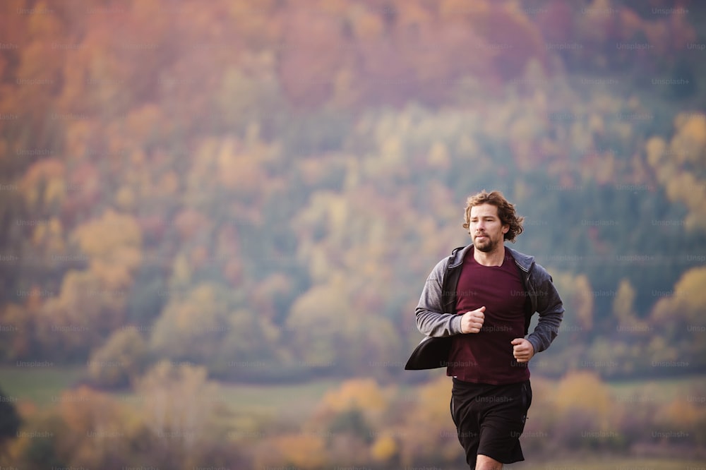 Young handsome runner outside in sunny autumn nature