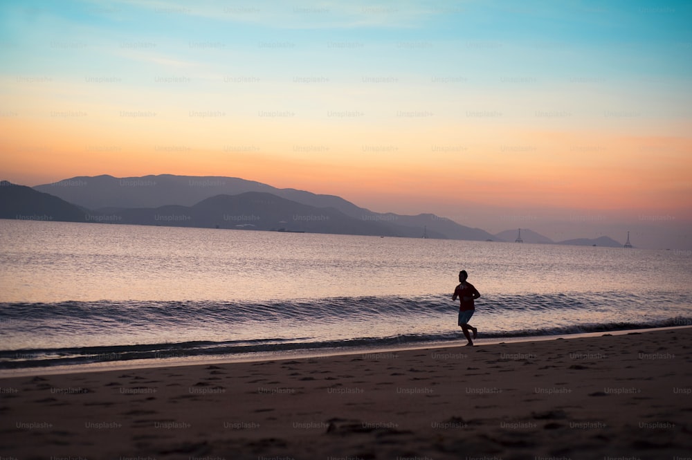 Jovem correndo na praia ao pôr do sol
