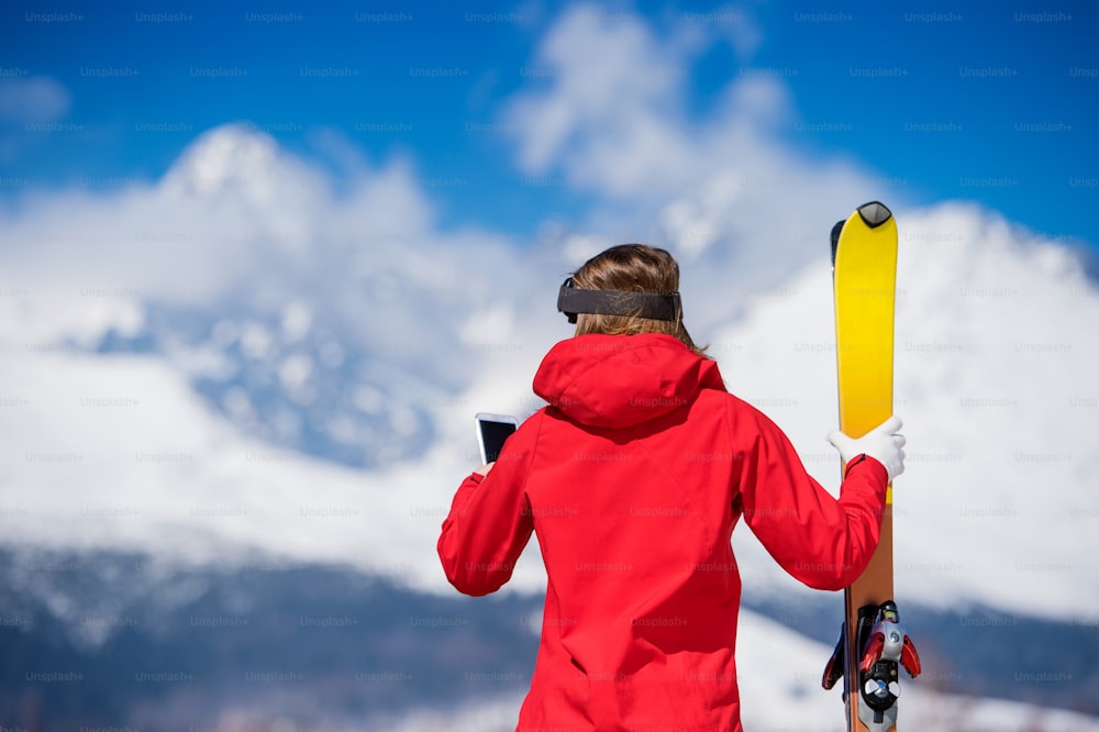 日当たりの良い冬の山々で外でスキーをする若い女性