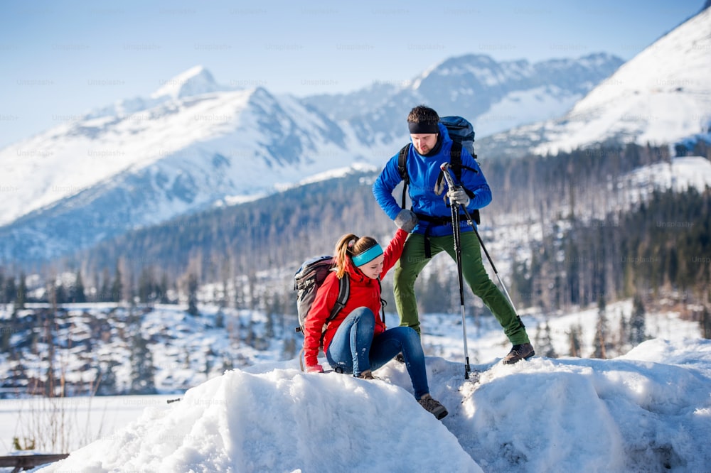 Young couple hiking outside in sunny winter mountains