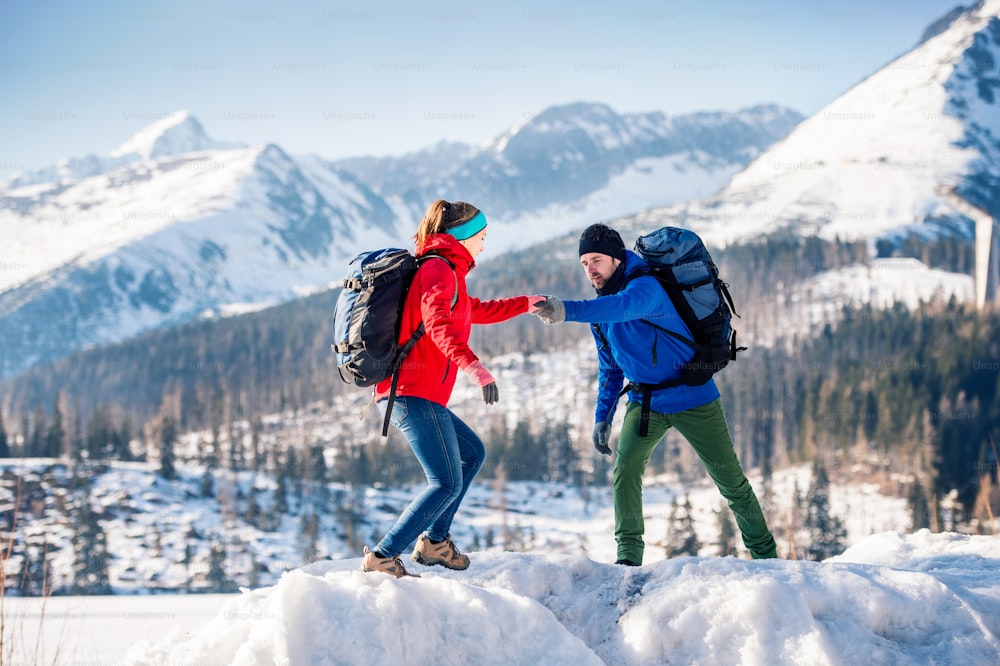 Young couple hiking outside in sunny winter mountains