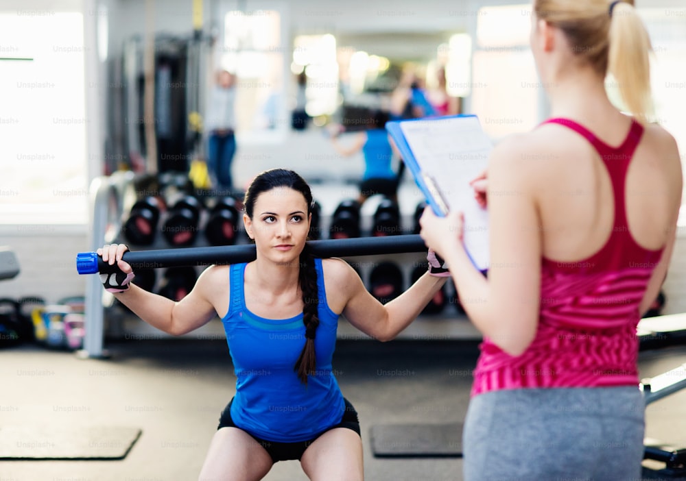 Two young beautiful women working out in gym