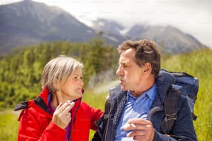 Senior hikers couple smoking during the walk in the mountains