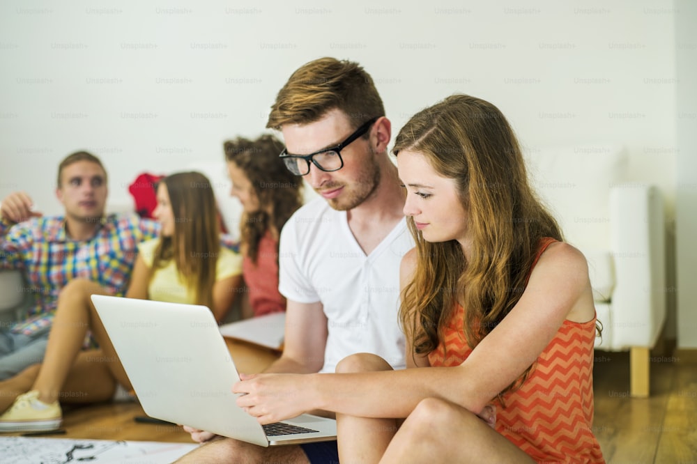 Group of young students studying together and preparing for exams in home interior