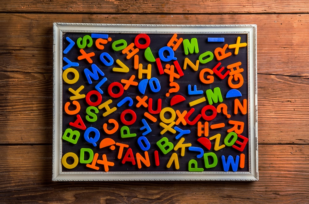 Lettres et chiffres en plastique colorés posés sur fond en bois.