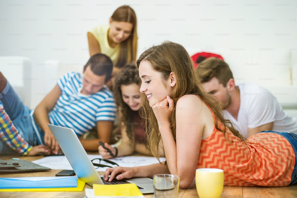 Group of young students studying together and preparing for exams in home interior