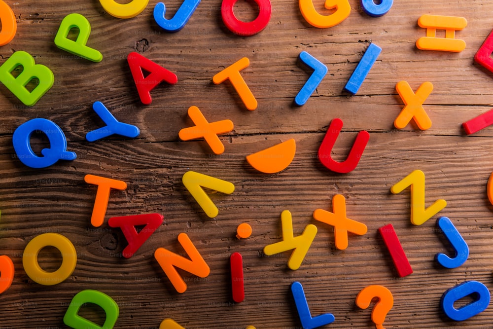 Colorful plastic letters and numbers laid on wooden background.