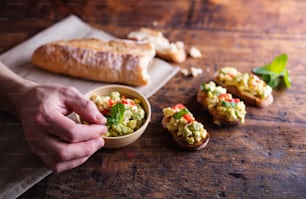 Spread made of avocado and other ingredients on slices of bruschetta. Studio shot on wooden background.