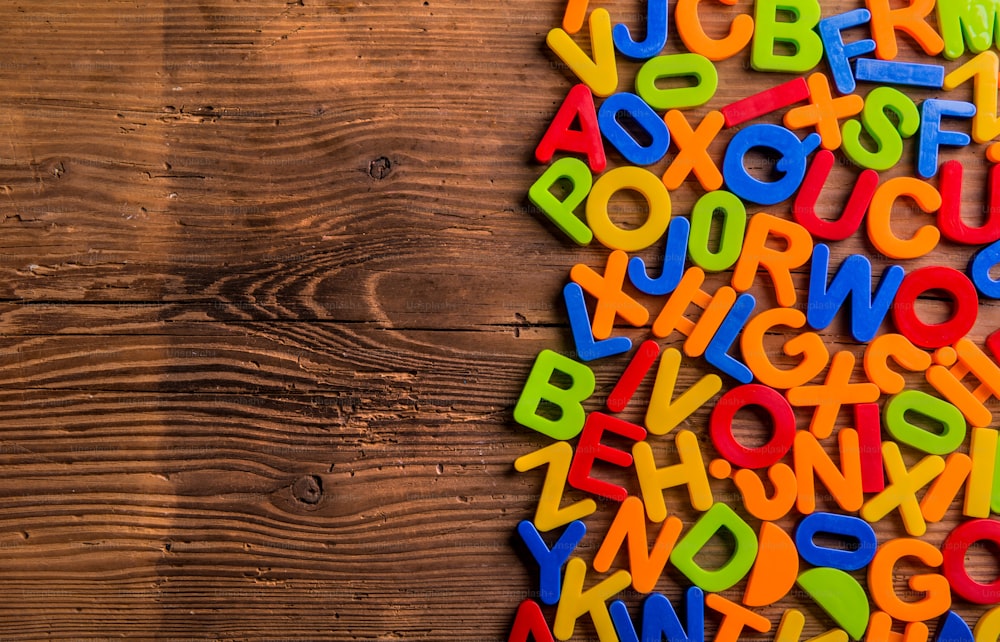 Colorful plastic letters and numbers laid on wooden background.