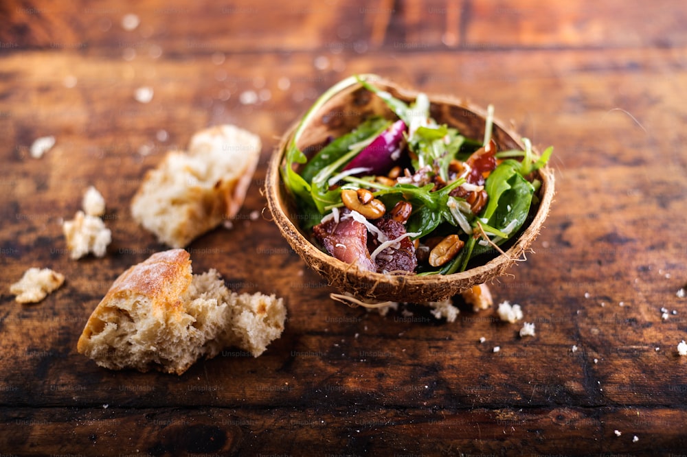 Rucola salad in a bowl made from coconut shell. Studio shot on wooden background.