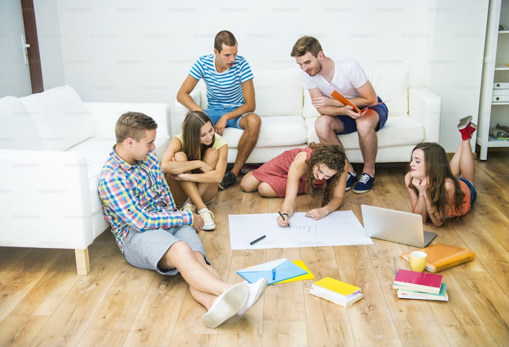 Group of young students studying together and preparing for exams in home interior