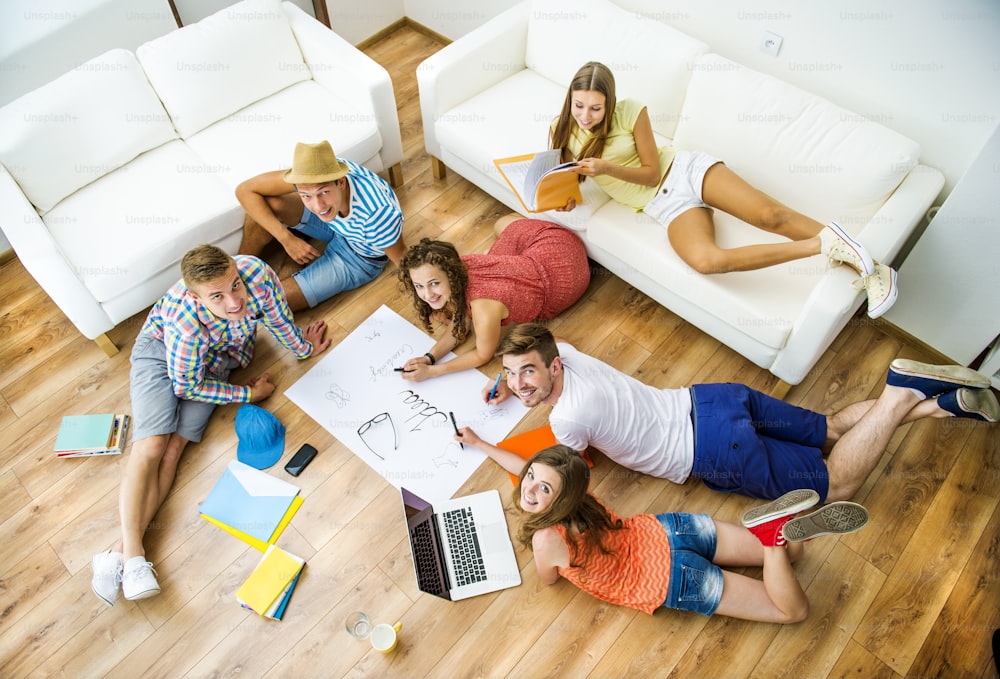 Group of young students studying together and preparing for exams in home interior