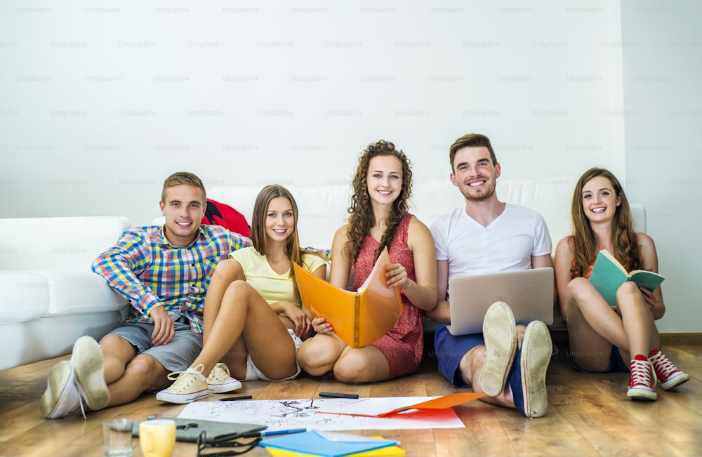 Group of young students studying together and preparing for exams in home interior