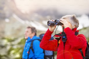 Senior hikers couple enjoying the landscape view with binoculars