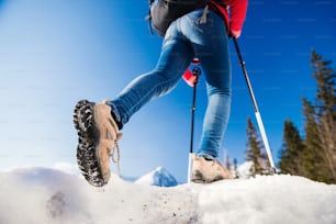 Femme méconnaissable faisant de la randonnée à l’extérieur dans les montagnes ensoleillées d’hiver