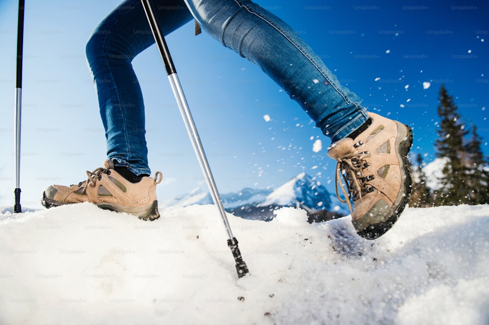 Unrecognizable woman hiking outside in sunny winter mountains