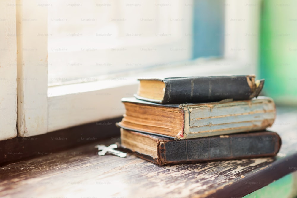 Pila di vecchi libri posati sul davanzale della finestra