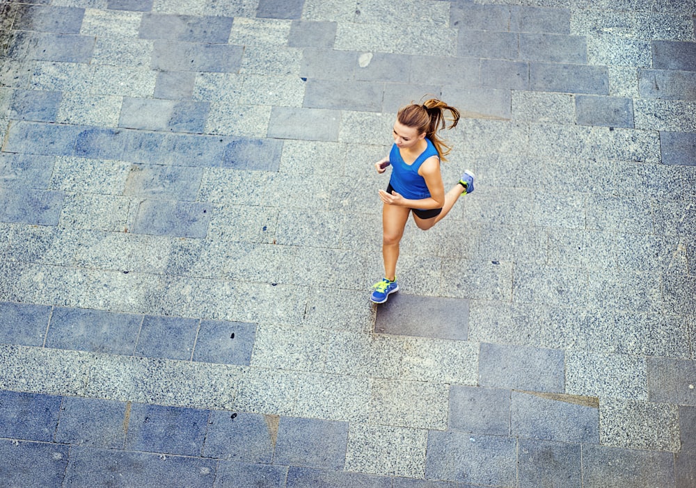 Vue grand angle d’une jeune coureuse faisant du jogging sur un trottoir carrelé, vieille ville au centre.