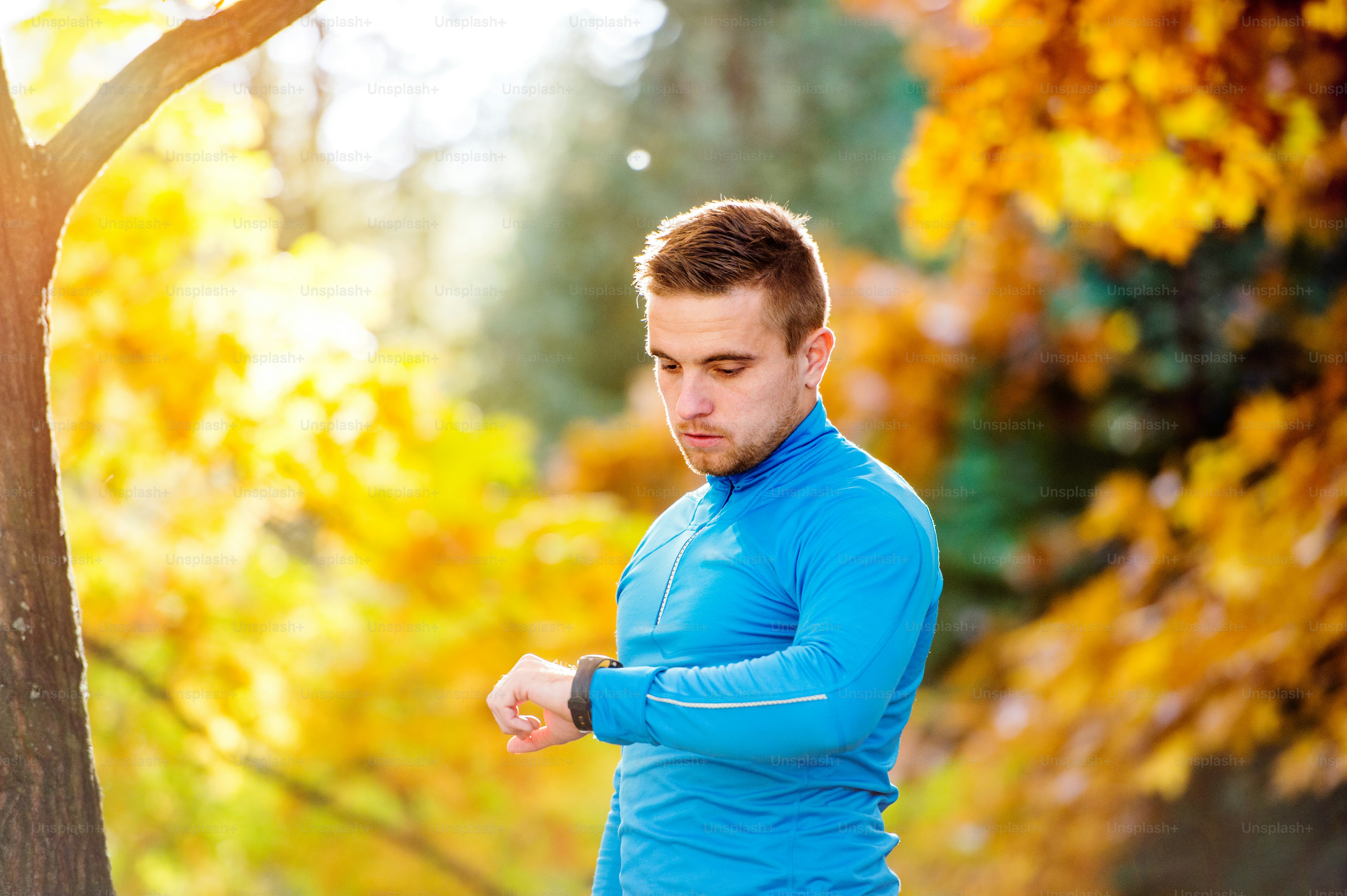Young handsome hipster runner in blue sweatshirt measuring time with