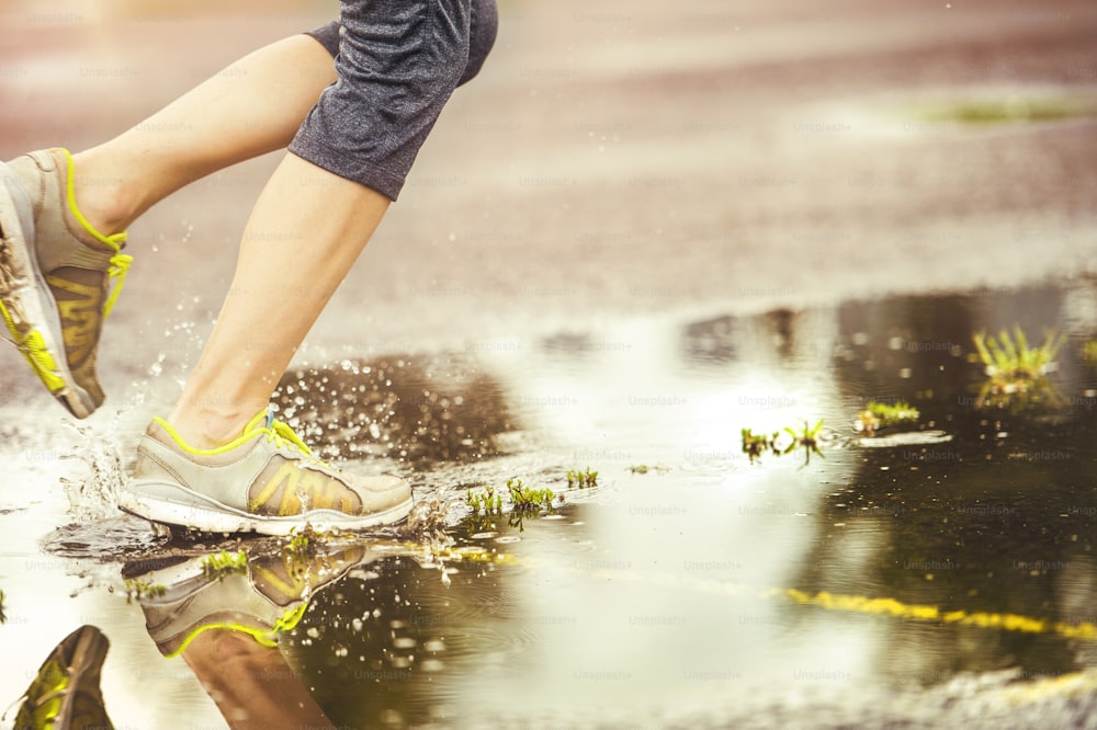 Young woman jogging on asphalt in rainy weather