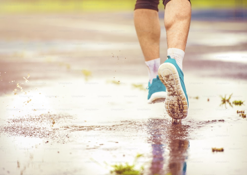 Young man jogging on asphalt in rainy weather