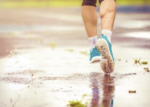 Young man jogging on asphalt in rainy weather