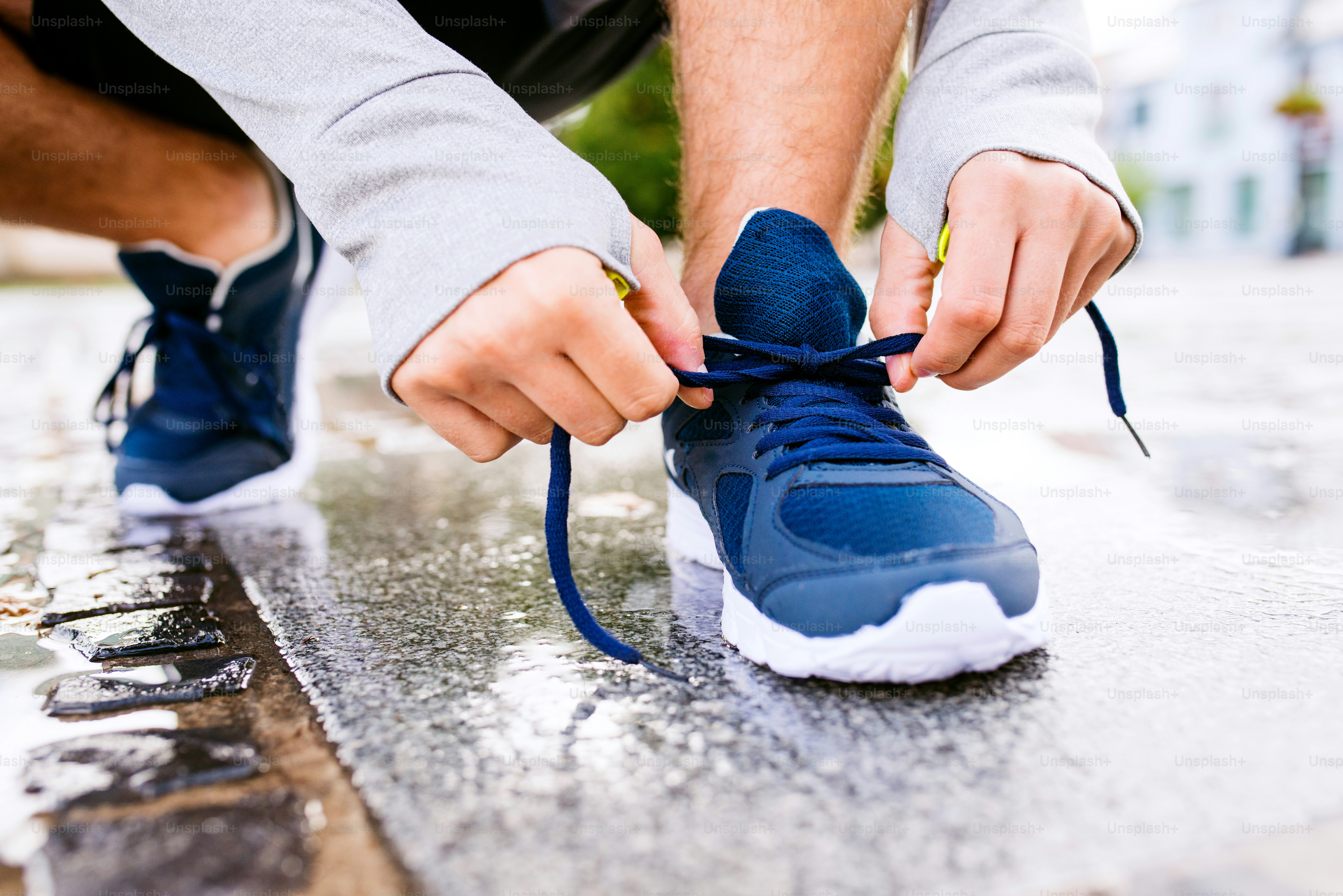 Close up of legs of unrecognizable man running in the town, puddle